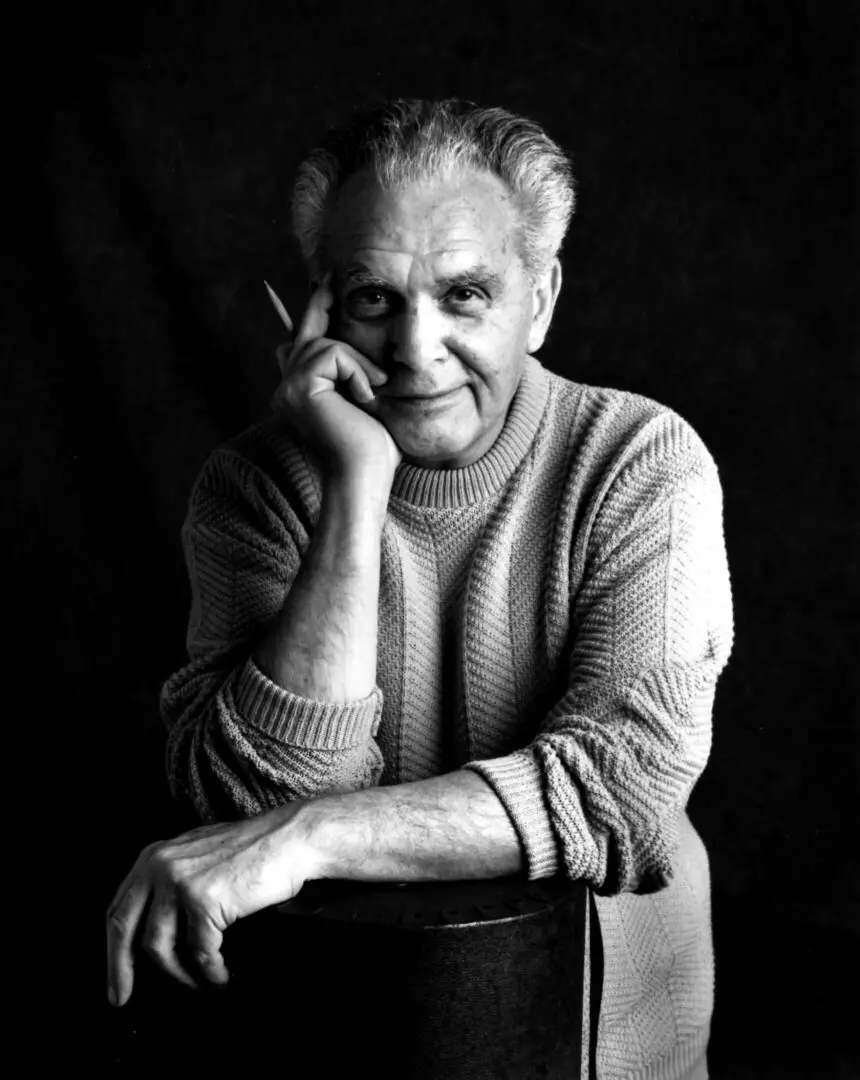 Black and white portrait of an elderly man smiling warmly.