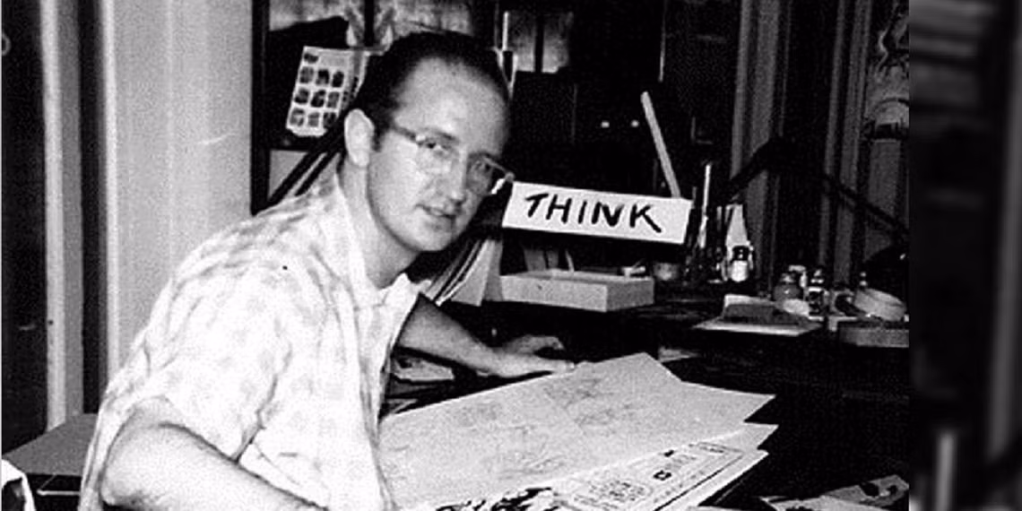 Man sitting at a desk with a 'THINK' sign in the background.