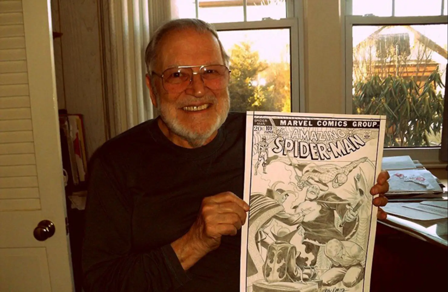 Smiling elderly man holding a Spider-Man comic book in a warmly lit room.